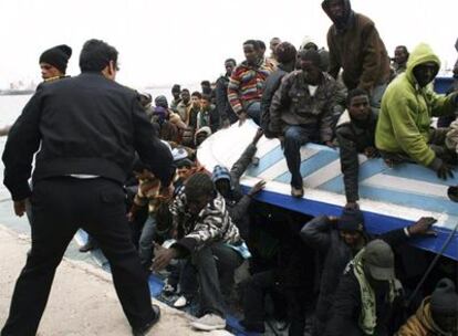 Un policía libio ayuda a desembarcar a unos inmigrantes rescatados tras llegar a Trípoli el domingo.