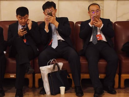 El uso del móvil para pagos en China se ha disparado. En la foto, varias personas consultan sus dispositivos durante el último congreso del Partido Comunista.