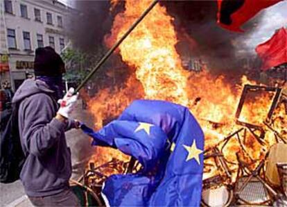 Un manifestante quema una bandera de la UE ante una barricada en Gotemburgo durante la cumbre europea.