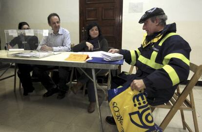 Un cartero deposita los votos por correo en una mesa electoral.