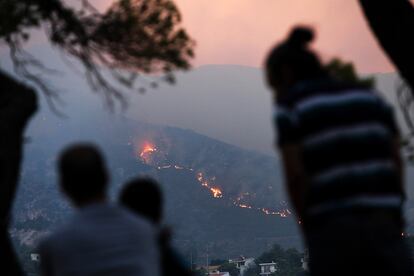 Vecinos de Penteli observan las llamas acercándose a las viviendas, este lunes. 