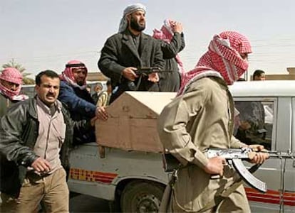 Milicianos suníes armados escoltan el féretro del jeque asesinado en Bagdad.
