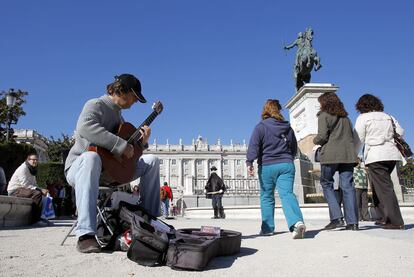 Un músico toca la guitarra ante el Palacio Real.