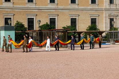 Soldados sostienen la bandera de España antes de su izado por el décimo aniversario del reinado de Felipe VI, este miércoles, en la plaza de Colón de Madrid. 
