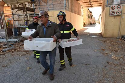 Dos bomberos ayudan a un hombre a llevar comida en el centro histórico de Norcia, el 31 de octubre.