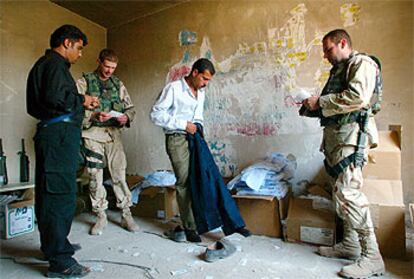 Un recluta de la policía iraquí se prueba el uniforme en presencia de dos soldados de EE UU.
