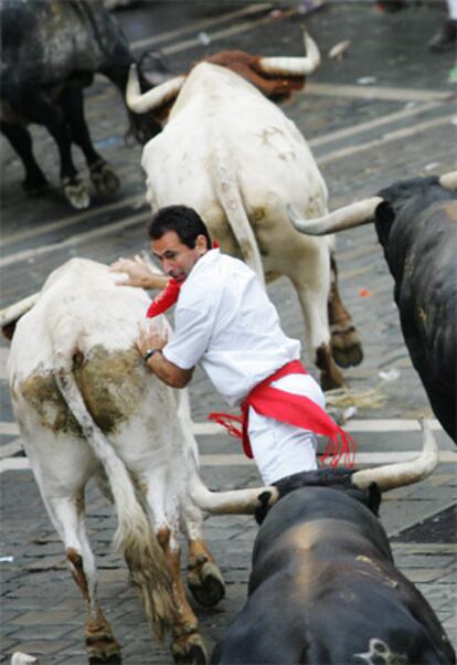 Un hombre corre entre varios toros, durante la tercera carrera de San Fermín 2007.