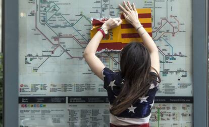 Una mujer vestida con una bandera de EE.UU arranca una bandera española en Barcelona.