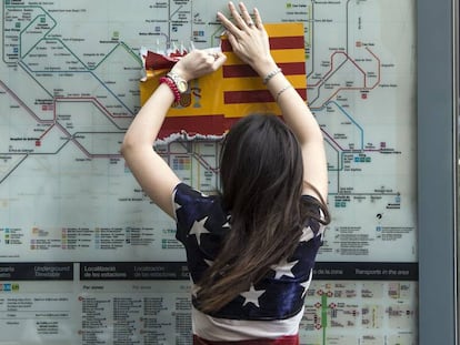 Una mujer vestida con una bandera de EE.UU arranca una bandera española en Barcelona.