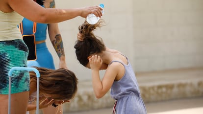 Varias madres del colegio Mediterráneo de Córdoba refrescan a sus hijas tras sacarlas del centro minutos antes de la hora de recreo, este martes.