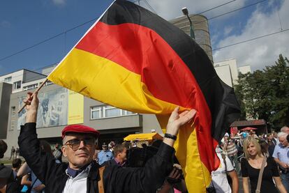 Un hombre alza la bandera alemana durante el acto de conmemoración de la construcción del Muro de Berlín
