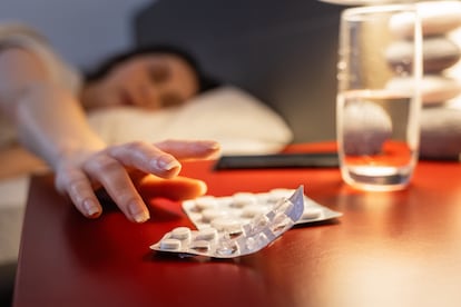Una mujer toma una pastilla contra el insomnio.