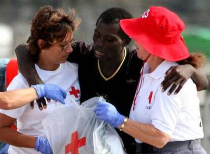 Miembros de la Cruz Roja ayudan a uno de los 90 inmigrantes que llegaron ayer a la playa de los Cristianos (Tenerife).