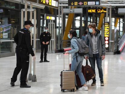 Dos viajeros y dos agentes, en el aeropuerto de Barajas el martes.