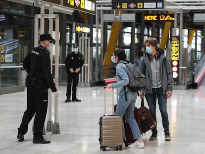 Dos viajeros y dos agentes, en el aeropuerto de Barajas el martes.