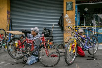Rolando Morales y Uriel Sánchez trabajan en bicicletas en un taller callejero en la colonia Centro Histórico en la Ciudad de México.
