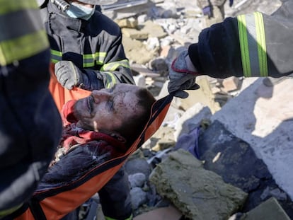 EDITORS NOTE: Graphic content / Rescuers carry a Ukrainian soldier saved after 30 hours from debris of the military school hit by Russian rockets, in Mykolaiv, southern Ukraine, on March 19, 2022. - Ukrainian media reported that Russian forces had carried out a large-scale air strike on Mykolaiv, killing at least 40 Ukrainian soldiers at their brigade headquarters. (Photo by BULENT KILIC / AFP)