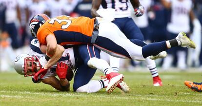 Shiloh Keo, de los Denver Broncos placa a Julian Edelman, de los New England Patriots