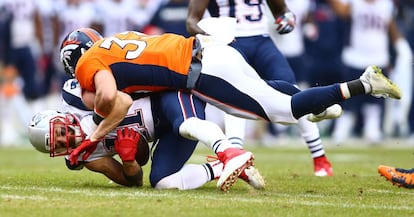 Shiloh Keo, de los Denver Broncos placa a Julian Edelman, de los New England Patriots