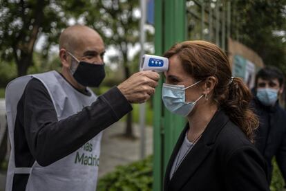 Un voluntario de Más Madrid toma la temperatura a Mónica García a la entrada de un acto celebrado en Leganés, el 24 de abril.