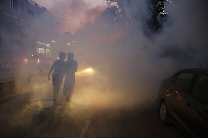 Chicos indios caminan más allá del humo de la fumigación que se lleva a cabo para evitar la propagación de enfermedades transmitidas por mosquitos en Allahabad (India).