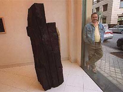 Koldobika Jauregi posa junto a su escultura en madera 'Asedio' a las puertas de la Galería Arteko, ayer en San Sebastián.
