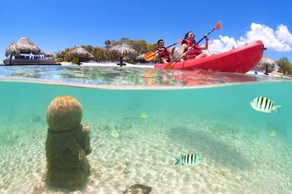 Una pareja en canoa y, bajo las aguas, unas ruinas mayas, en Roatán (Honduras).