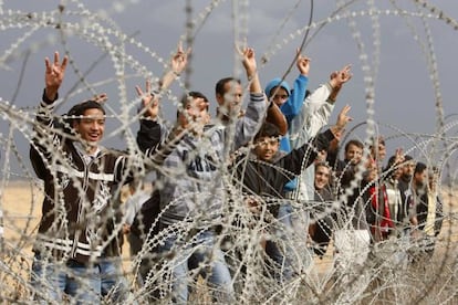 Un grupo de palestinos hacen gestos de victoria junto a una alambrada de la frontera entre el sur de Gaza e Israel.