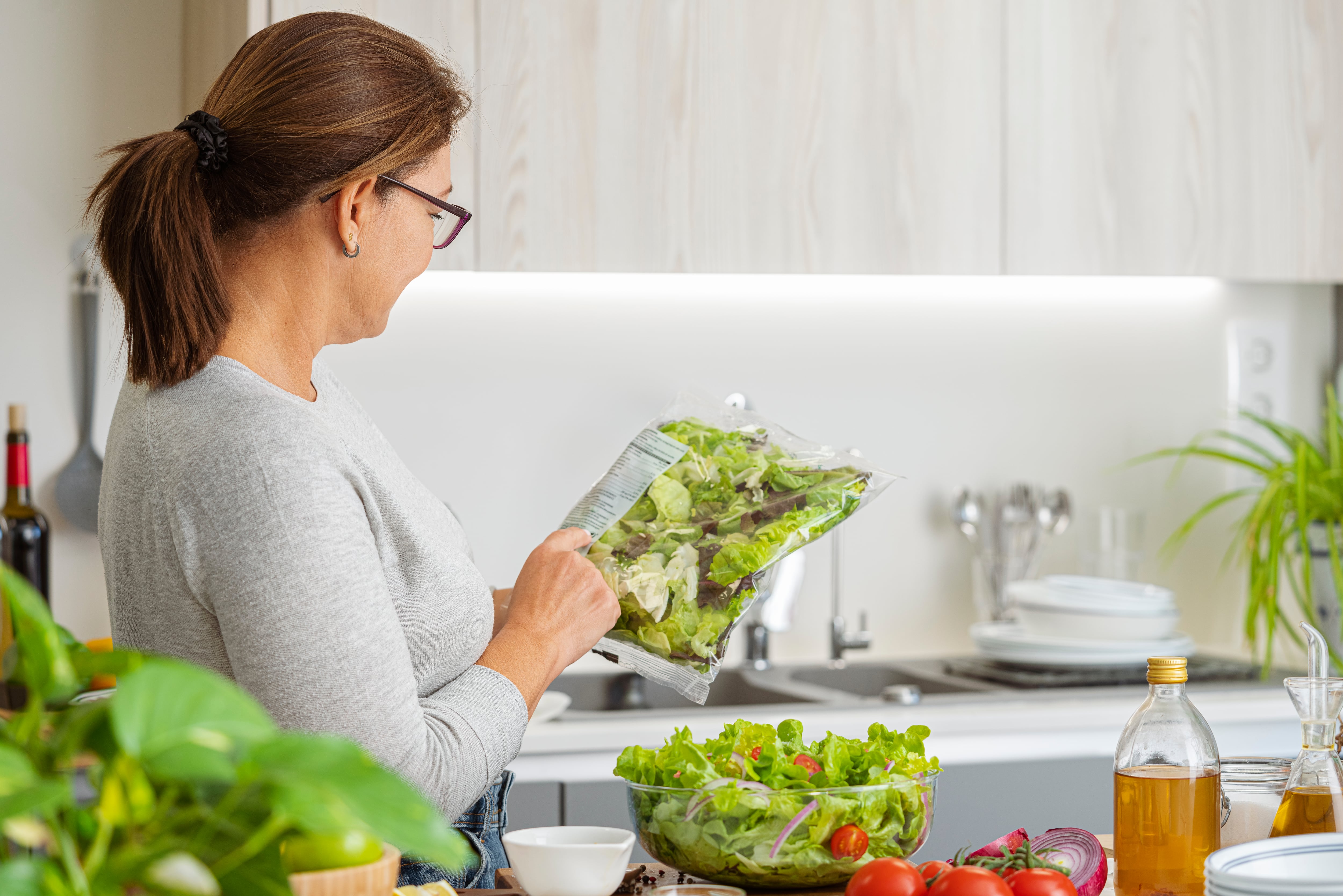Una mujer lee el etiquetado de una ensalada en bolsa.