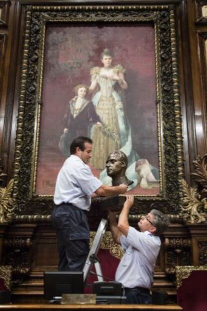 Dos operaris retiren el bust de Joan Carles I a l'Ajuntament de Barcelona.