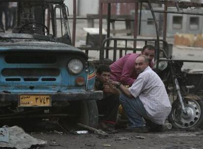 Varios residentes de Ciudad Sader se refugian para protegerse de los disparos al aire del Ejército iraquí para repeler las protestas tras dos atentados con coche bomba.