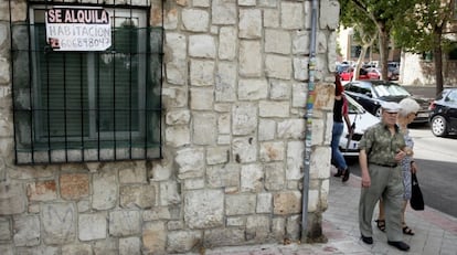 Una pareja pasa al lado de un cartel que anuncia una habitación en alquiler.