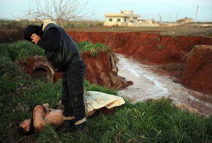 Un hombre inspecciona un cuerpo no identificado después del ataque del Ejército en Idleb, Siria.