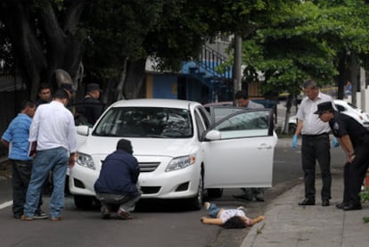 El cadáver de Claudia de Medina yace en el suelo mientras la policía investiga el automóvil atacado