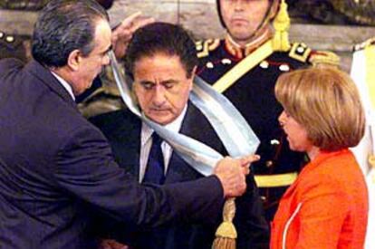 El presidente del Parlamento, Eduardo Camaño, coloca la banda presidencial sobre Duhalde, contemplado por su esposa, Hilda.