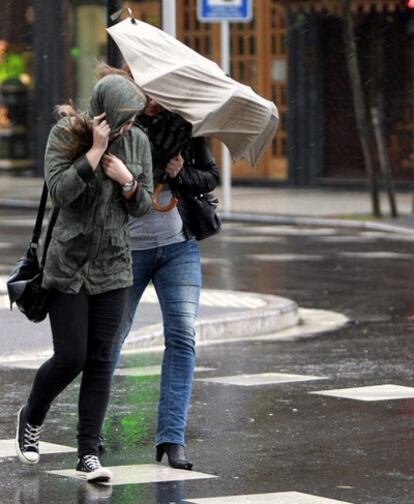Dos mujeres pelean con la lluvia y el viento hoy en San Sebastián.