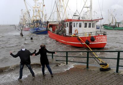 Una joven pareja juega con las olas en el puerto de Dornumer Siel meintras la tormenta "Xaver" golpea el norte en Alemania.