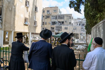 Varias personas contemplan una sinagoga dañada en Israel por ataques de Irán.
