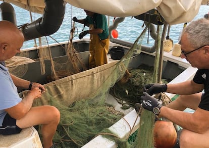Dos pescadores en el puerto de Burriana arreglan las redes después de faenar. |
