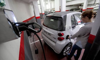 Una usuaria recarga un coche eléctrico en un garaje.