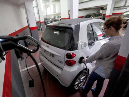 Una usuaria recarga un coche eléctrico en un garaje.