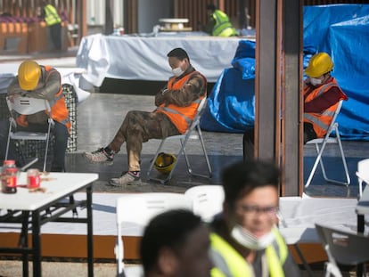 Varios operarios, algunos de ellos cono mascarillas sanitarias, parados en un patio del recinto de Fira Barcelona.