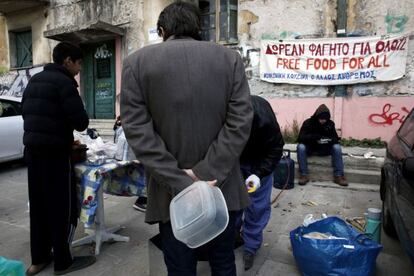Personas 'sin techo' reciben comida en una calle en el centro de Atenas.