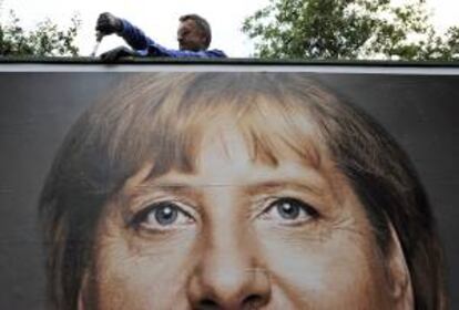 Un trabajador retira hoy un cartel electoral con el rostro de la canciller alemana, Angela Merkel, en Itzehoe (Alemania).