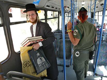 Un judío ultraortodoxo y una policía israelí viajan a bordo de un autobús casi vacío en Jerusalén.