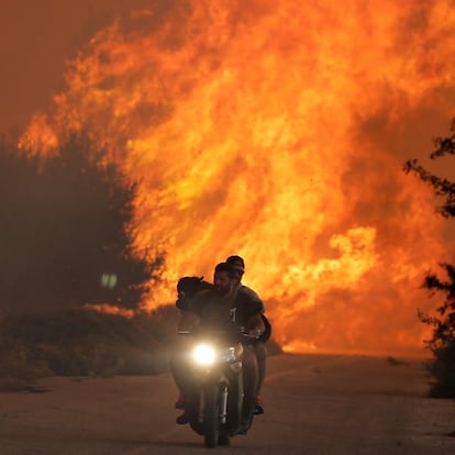 Dos personas huyen con su perro de un incendio en el norte de Atenas el pasado día 14.