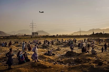 Un avión militar de carga sobrevuela Kabul, mientras decenas de afganos que tratan de abandonar el país tras el regreso de los talibanes esperan a las afueras del aeropuerto, el 23 de agosto de 2021. Imagen de Marcus Yam ganadora del Pulitzer a la mejor fotografía informativa de última hora, facilitada por 'Los Angeles Times'. 