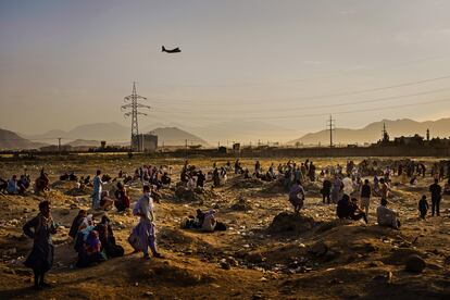 Un avión militar de carga sobrevuela Kabul, mientras decenas de afganos que tratan de abandonar el país tras el regreso de los talibanes esperan a las afueras del aeropuerto, el 23 de agosto de 2021. Imagen de Marcus Yam ganadora del Pulitzer a la mejor fotografía informativa de última hora, facilitada por 'Los Angeles Times'.