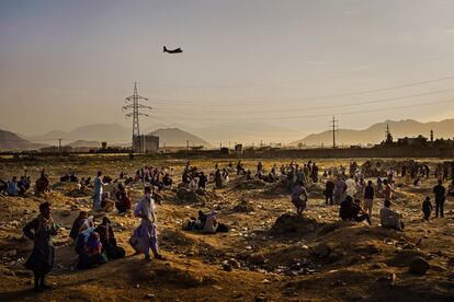 Un avión militar de carga sobrevuela Kabul, mientras decenas de afganos que tratan de abandonar el país tras el regreso de los talibanes esperan a las afueras del aeropuerto, el 23 de agosto de 2021. Imagen de Marcus Yam ganadora del Pulitzer a la mejor fotografía informativa de última hora, facilitada por 'Los Angeles Times'. 