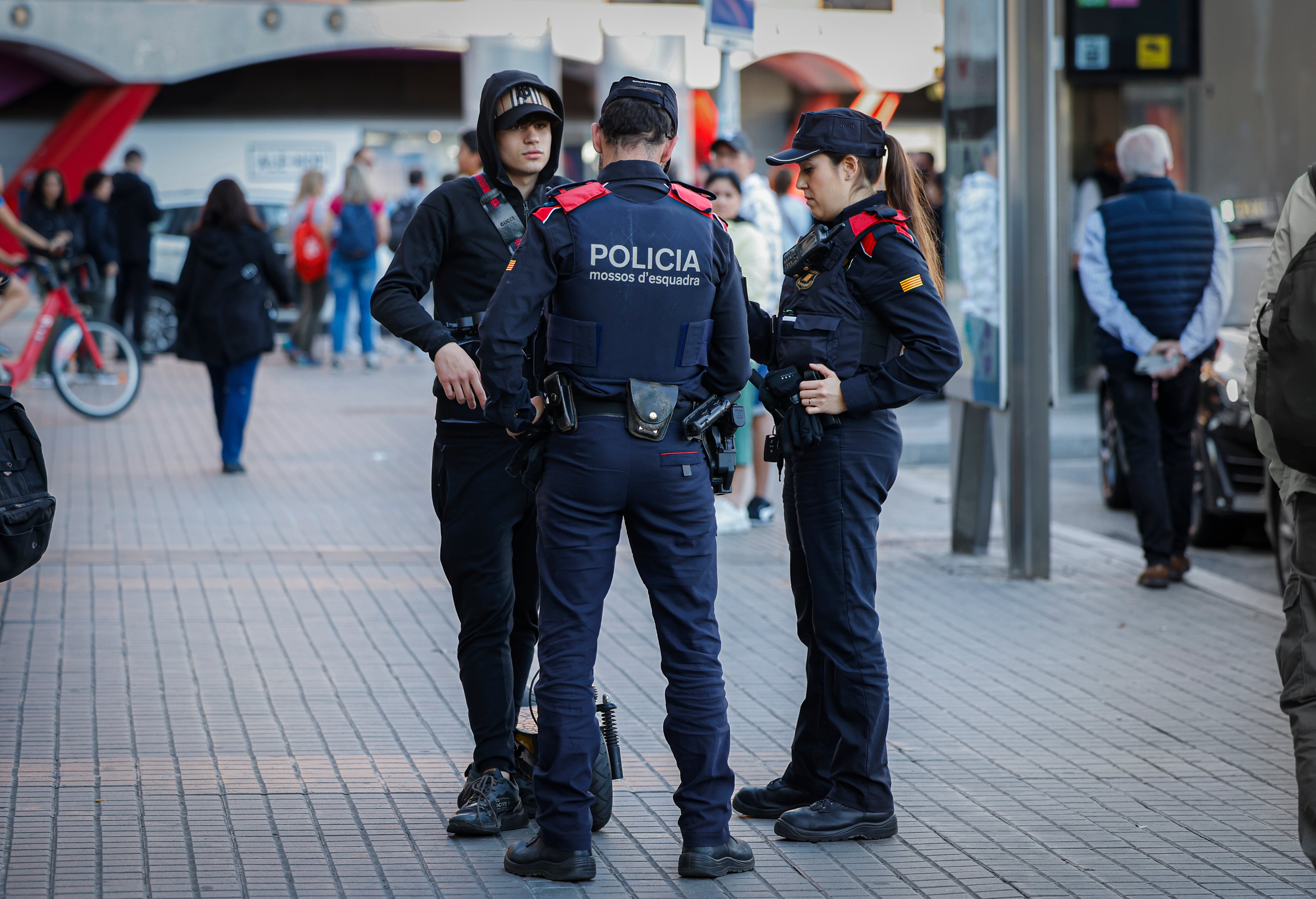 Los mossos d'esquadra paraban en 2024 a un joven que circula por la acera en patinete, en la plaza de España, en Barcelona.